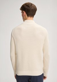 Maglione a maglia color crema con motivo a trama, collo e polsini a costine, silhouette aderente e orlo dritto.