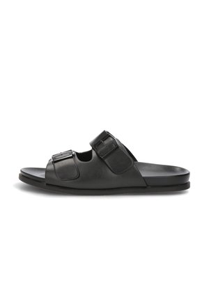 Sandalia negra tipo sandalia con dos correas ajustables con hebilla y suela plana, mostrada de perfil sobre un fondo blanco.