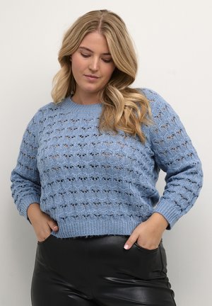 Jasnoniebieski sweter z dzianiny, charakteryzujący się teksturowanym, otwartym wzorem koronkowym, okrągłym dekoltem i ściągaczami, w zestawie z czarnymi skórzanymi spodniami.