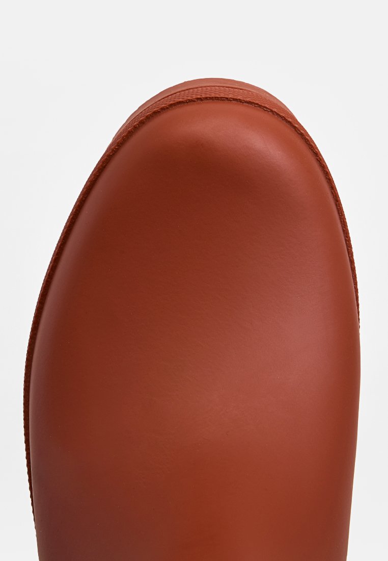 Bruine leren laars met een ronde neus, een gladde textuur en minimale stiksels. Het bovenwerk is naadloos met een glanzende afwerking.