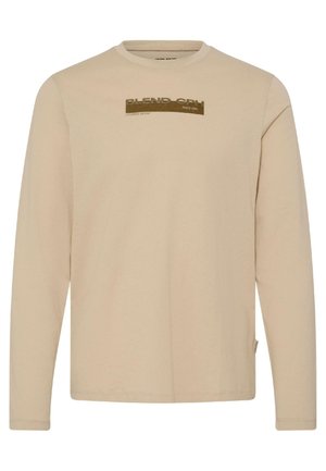 Maglietta beige a maniche lunghe in tessuto morbido, con un logo rettangolare in marrone scuro e testo a contrasto sul petto. Classico scollo rotondo.