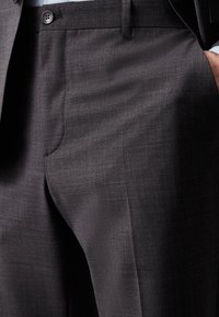 Dunkelgraue maßgeschneiderte Hose aus glattem Stoff, mit einem einzigen Knopfverschluss, Taschendetails und einer taillierten Passform.