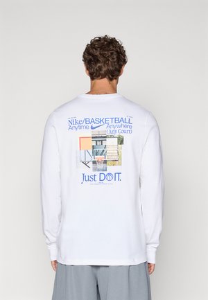 Hvid langærmet t-shirt med grafisk tryk på ryggen, der viser forskellige elementer fra en basketballbane og teksten "Just DO IT." i blå.