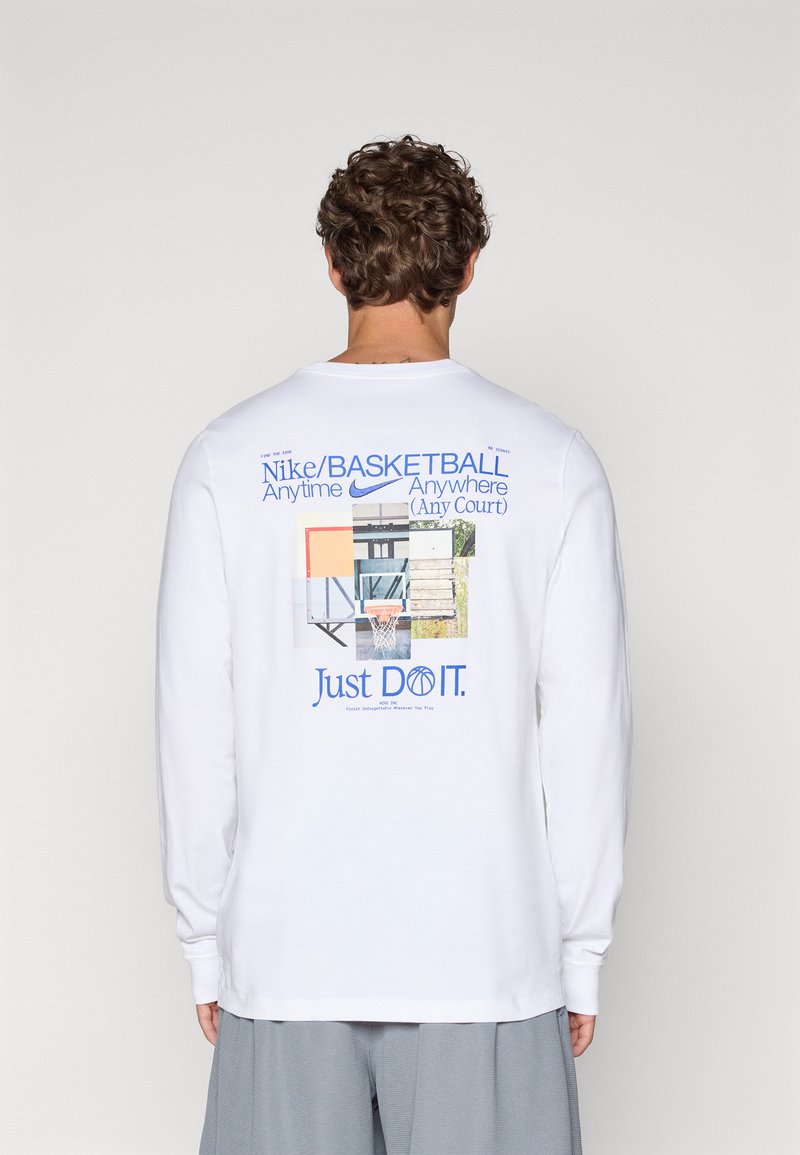 Hvid langærmet t-shirt med grafisk tryk på ryggen, der viser forskellige elementer fra en basketballbane og teksten "Just DO IT." i blå.