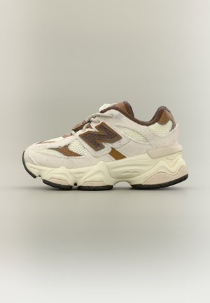 Beiger und brauner New Balance Sneaker mit Mesh- und Veloursleder-Obermaterial, dicker profilierter Sohle und "N"-Logo an der Seite, im Seitenprofil gezeigt.