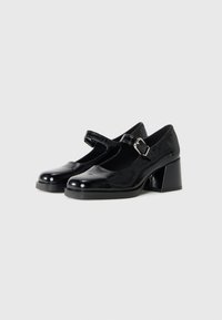 Des chaussures Mary Jane en cuir verni noir avec un design à bouts carrés, une bride réglable avec boucle et un talon bloc. Texture lisse et finition polie.