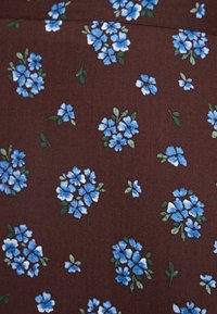 Tela marrón con un patrón floral que presenta grupos de flores azules y hojas verdes. La textura parece suave, con un acabado mate.