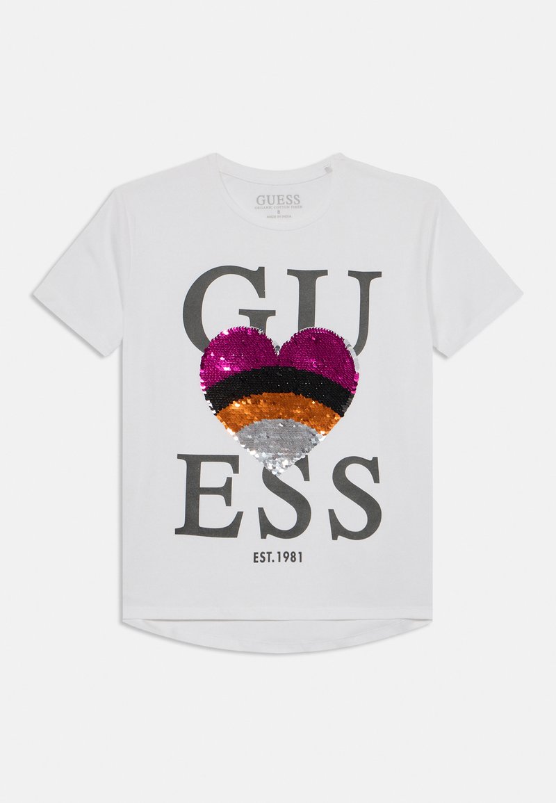 White cotton t-shirt featuring the text "GUESS" in gray, with a multi-colored sequined heart design in pink, black, orange, and silver.