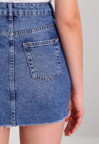 Džínová mini sukně světle modré barvy s třepeným lemem, detaily na zadních kapsách a přiléhavým střihem. Viditelné švy a vysoký pas.