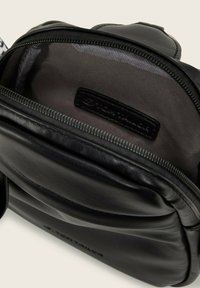 Sac en cuir noir avec une ouverture zippée. L'intérieur présente une doublure grise et une étiquette de marque. Surface texturée et forme arrondie.