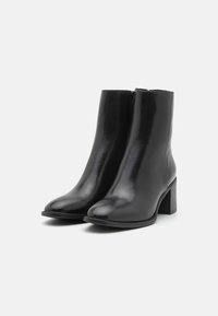 Black leather ankle boots with a smooth texture, rounded toe, side zipper, and a chunky heel. Features minimal stitching and sleek design.