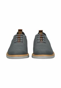 Scarpe di rete grigie con punta rotonda e accentatura marrone sulla linguetta. Suola in gomma con rifinitura in pelle beige. Sei fori per i lacci.