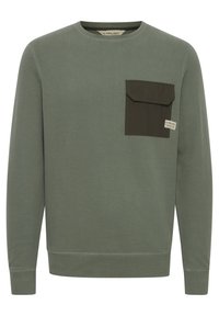 Green sweatshirt made of cotton, featuring a contrasting dark green patch pocket on the left chest, round neck, and long sleeves.