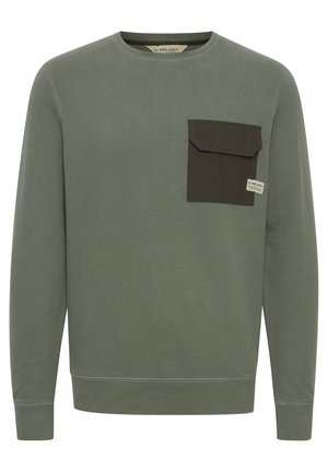 Sweatshirt vert en coton, doté d'une poche patch contrastante vert foncé sur le côté gauche de la poitrine, col rond et manches longues.