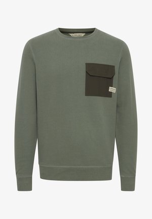 Zelená mikina vyrobená z bavlny, s kontrastnou tmavozelenou náprsní kapsou na ľavej hrudi, okrúhlym výstrihom a dlhými rukávmi.