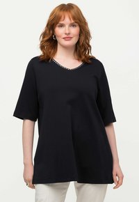 Sort T-shirt med korte ærmer og V-hals i en afslappet pasform, med en metallisk kant langs halsudskæringen og en glat bomuldsstruktur.