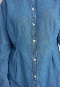 Lichtblauw denim overhemd met een knoopsluiting aan de voorkant met witte knopen, een iets losse pasvorm en een zachte structuur met een klassieke kraag.