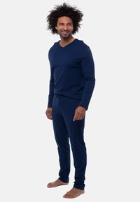 Marineblaues Freizeitanzugset aus weichem Stoff; verfügt über lange Ärmel, ein V-Ausschnitt-Oberteil und elastische Hosen mit einem Kordelzug.