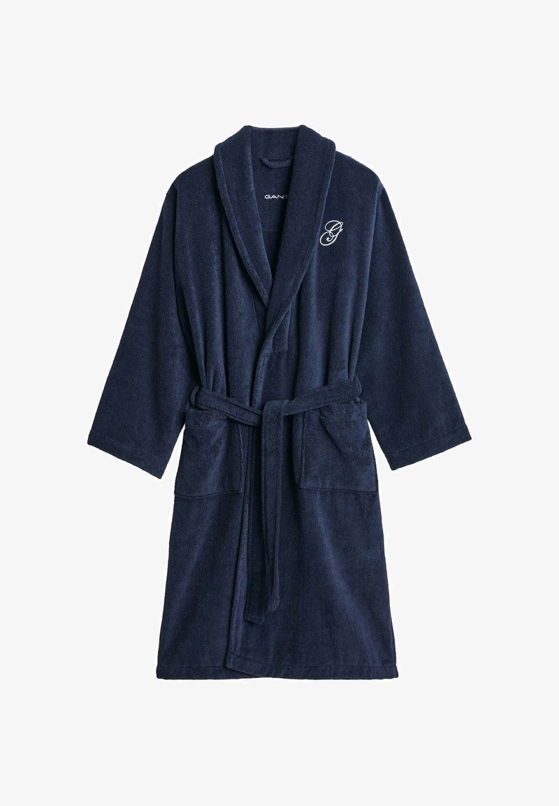 Marineblauer Frottierbademantel mit langen Ärmeln, Schalkragen, Gürtel und zwei vorderen Taschen. Verfügt über ein auf der Brust gesticktes Logo.