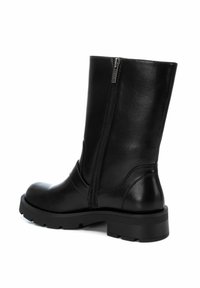 Bota de cuero negra hasta la rodilla con textura suave, cremallera lateral y suela resistente que presenta un ligero tacón y un diseño de punta redondeada.