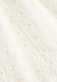 Tessuto bianco ricamato con un motivo testurizzato di ovali intrecciati e accenti floreali, con piccoli dettagli a taglio sparsi.