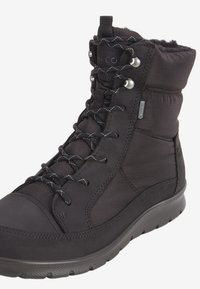 Botas negras de media caña con punta de cuero suave y parte superior de tela blanda. Cuentan con un diseño de cordones y suela de goma texturizada para mayor tracción.
