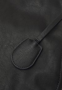 Sacchetto di cuoio nero con una texture liscia, caratterizzato da un cappuccio arrotondato con dettagli di cucitura e una cinghia sottile.
