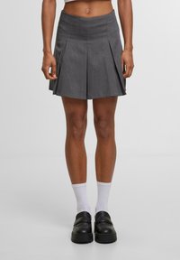 Hame harmaa laskostettu, valmistettu sileästä kankaasta, jossa on tiukka vyötärö ja joka ulottuu polvien ylle. Korostettu terävillä laskoksilla.