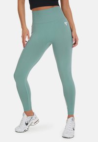 Teal hoge taille legging met een gladde textuur en een aansluitend ontwerp; heeft een witte logo-accent op de dij en zijdetaillering.
