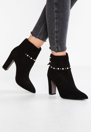 Stivaletti neri in suede con punta affusolata, tacco spesso e hardware decorativo con accenti di perle sul polsino.