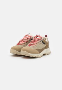 Beige Wanderschuhe mit pinken Schnürsenkeln, strukturiertem Obermaterial, Gummisohlen und verstärkten Ösen. Sie besitzen kontrastierende Farbakzente und ein robustes Design.