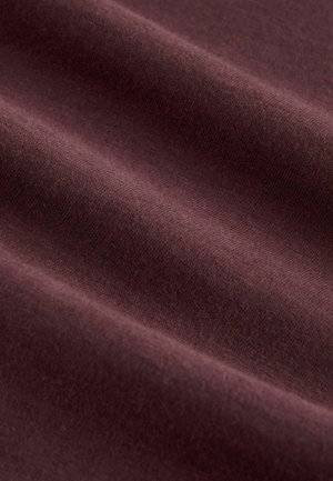 Textil in einem tiefen Burgunderrot mit einer weichen, glatten Textur. Falten erzeugen sanfte Wellen über die Stoffoberfläche und betonen den reichen Farbton.