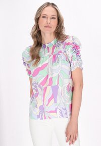 Mønstret bluse med blomster i flere farver, med smocked halsudskæring, puffede ærmer og glat stof; har pastelfarver i grøn, pink og lilla.