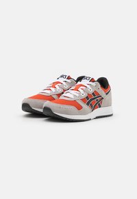 Scarpe atletiche rosse e grigie con lacci bianchi, materiali in rete e suede, dettagli neri e suole in gomma. Presenta il logo sulla linguetta.