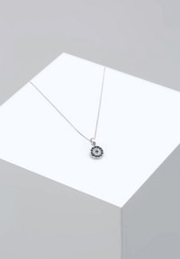 Sølv halskæde med en rund vedh�æng. Vedhænget har et blomster mønster med blå og klare sten. Kæden er slank og delikat.