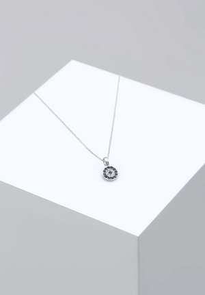 Sølv halskæde med en rund vedhæng. Vedhænget har et blomster mønster med blå og klare sten. Kæden er slank og delikat.