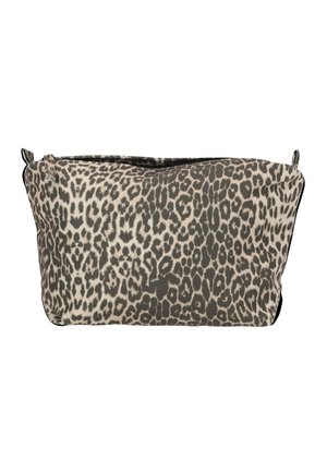 Kvinde iført hvid bluse med lange ærmer og mørke leggings holder en leopardprint clutch mod en ensfarvet hvid baggrund.