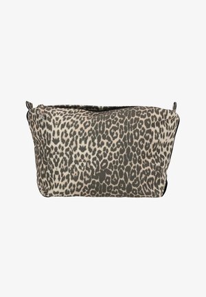 Kvinde iført hvid bluse med lange ærmer og mørke leggings holder en leopardprint clutch mod en ensfarvet hvid baggrund.