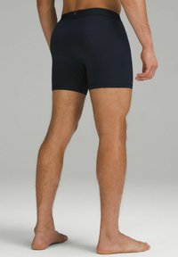 Tumedate sinised bokserid, mis on valmistatud elastsetest materjalidest, sujuva vöökohaga, sobiva disainiga ja reie keskosa pikkusega.