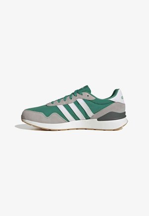 Zapatilla deportiva verde y gris con parte superior de ante, que presenta tres rayas blancas, lengüeta acolchada y suela de goma con detalle marrón claro.