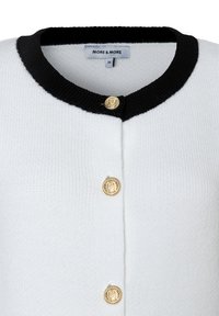 Witte cardigan met een zwarte geribbelde halslijn, voorzien van drie gouden knopen met een textuurtje, gemaakt van een gebreide stof.