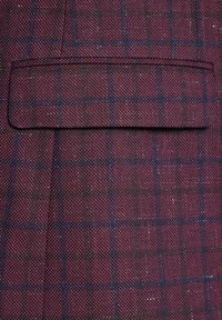 Bordowa tkanina o fakturze z delikatnym wzorem w kratę w kolorze granatowym i ciemnozielonym. Zawiera kieszeń z wypustką z przeszytymi brzegami.