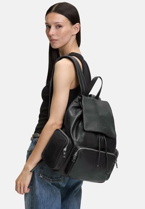 Schwarzer Leder-Rucksack mit einer Kordelzugverschluss, umschlagbarem Deckel und zwei vorderen Reißverschlusstaschen. Merkmale sind eine glatte Textur und minimalistisches Zubehör.