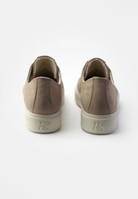 Chaussures slip-on en cuir beige avec une finition texturée, arrière arrondi et semelle en caoutchouc de couleur claire contrastante avec logo en relief.