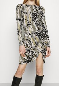 Langärmeliges Kleid mit abstraktem Muster in Schwarz, Weiß und Beige, seitlichem Schlitz und gerafften Details an der Taille.