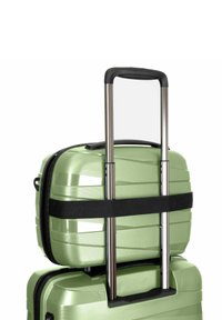 Groene harde koffer met telescoophandvat, kleinere koffer bovenop vastgezet met een zwarte riem, geïsoleerd op een witte achtergrond.