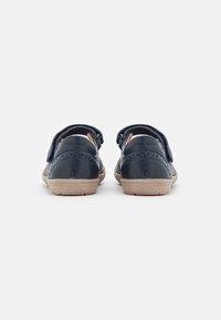 Sandalias de cuero azul marino con un acabado suave, que cuentan con una correa de velcro y una suela de goma beige, diseñadas para la comodidad y facilidad de uso.