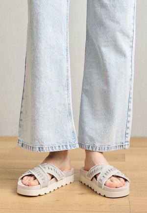 Heledad hallhalli platvormsandaalid, millel on tekstuuriga kangast rihmad ja kummist tallad, pakuvad mugavust paksu polsterdatud alusega. Näha on teksast flöödid.