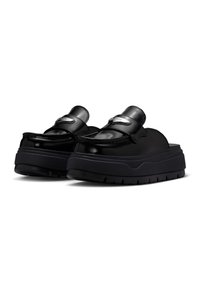 Mules de plataforma negros con parte superior de cuero brillante, puntera redondeada, correa ajustable y suela de goma texturada gruesa.