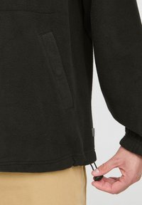 Black fleece pullover with a front pocket, adjustable hem cord, and ribbed cuffs. Soft texture with a relaxed fit and minimal detailing.